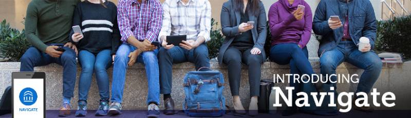 Students sitting on retaining wall looking at phones